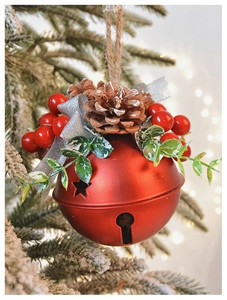 Detail of red matte Christmas bell with pine cones, berries and ribbon on snow-covered tree