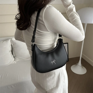 French retro black croissant bag with silver bow accent shown on model in home setting