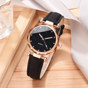 Detail of rose gold quartz watch with starry dial and faceted glass on wooden surface