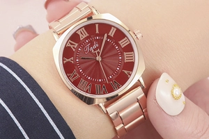 Close-up of rose gold lady watch featuring red sunray dial and Roman numeral markers