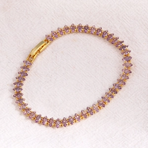 Detail of marquise-cut purple stones in a gold knotted tennis bracelet with a fold-over clasp