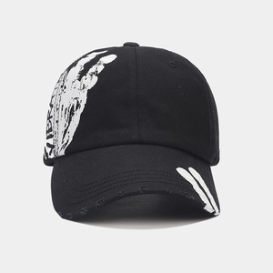 Detail of black cotton baseball cap with white skeleton hand print and distressed brim