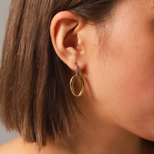 Close-up of model wearing two-tone geometric oval earrings in gold and silver finish