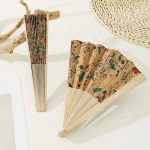 Vintage Portuguese cork folding fan with colorful floral and insect prints on light wood