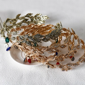 Close-up of stacked metal leaf tiaras in gold, silver and bronze with sparkling rhinestones