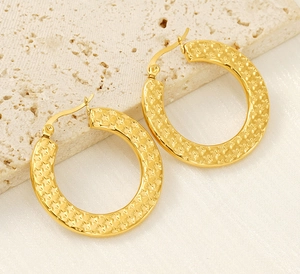 Close-up of golden stainless steel hoop earrings featuring embossed star patterns and textures