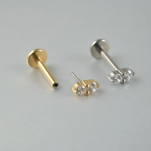 Détail de clous d'oreilles en titane argent et or avec zircons cubiques transparents