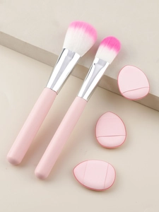 Close-up of pink makeup brushes and thumb puffs arranged on minimalist stone blocks
