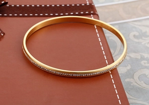 Dettaglio di un bracciale in acciaio inossidabile dorato con strass brillanti su una confezione