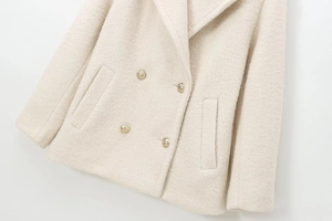 Detailed macro view of double-breasted buttons on off-white textured wool coat