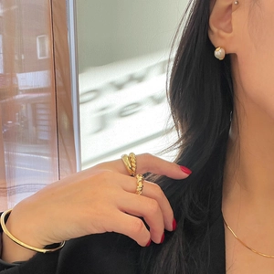 Detail shot of elegant gold twisted ring and pearl earring set on a model