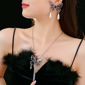 Close-up of butterfly necklace set with green gemstones and white pearls on a model