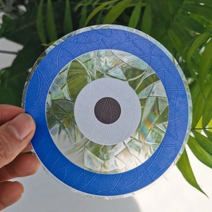 Rainbow suncatcher prism window cling with circular blue pattern held against green leaves