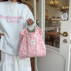 Detail of pink floral quilted tote bag with green handles and zakka logo label