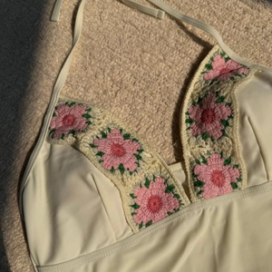 Detail of cream high-waisted bikini featuring handmade pink crochet floral accents