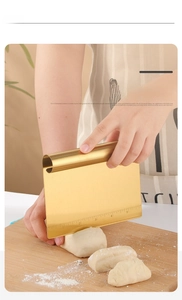 Golden stainless steel dough scraper with measurements cutting dough in the kitchen