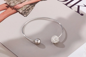 Détail d'un bracelet jonc argenté en C avec une bille polie et une bille sertie de cristaux