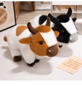 Close-up of soft plush brown and black cartoon cows in a cozy decorative desktop scene