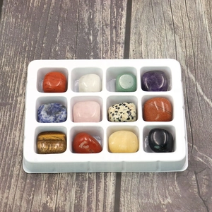 Macro view of 12 assorted polished natural gemstones and crystals in a white tray