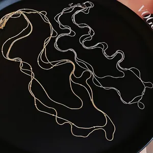 Minimalist gold and silver triple-layered tassel necklaces with small beads on a tray