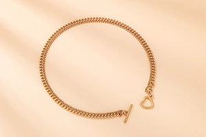 Detail of golden Cuban link chain featuring a decorative heart-shaped toggle clasp