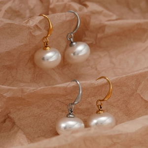Elegant stainless steel pearl drop earrings in gold and silver options on brown paper