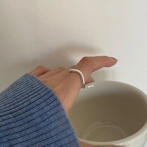 Close-up of a silver wavy geometric open ring worn on a finger during daily use
