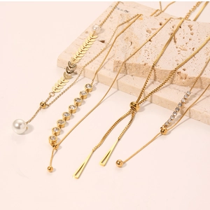 Detail view of gold necklaces with pearls, zircons, and geometric pendants on stone