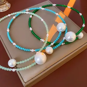 Three beaded pearl necklaces in green and blue colors on a brown jewelry display box