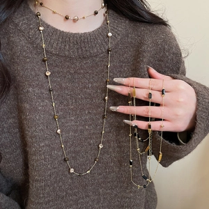 Close-up of layered bohemian tiger eye bead necklace with pearls and metallic chains