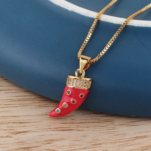 Macro shot of red enamel horn pendant with colorful zircons and golden chain
