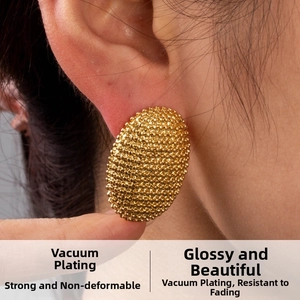 Macro shot of gold-plated oval earrings featuring a vintage beaded grain texture