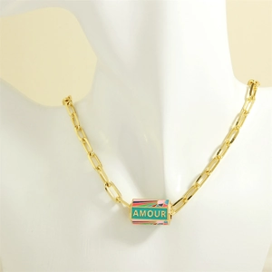 Detail of gold chunky chain necklace featuring a colorful enamel AMOUR pendant on a bust