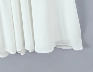 Vue macro détaillée de l'ourlet de la robe en mousseline blanche avec texture fluide