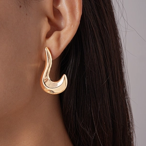Close-up of golden irregular geometric hoop earring with polished metallic finish