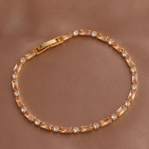 Golden bracelet detail with champagne rectangular gems and round zircons on silk background