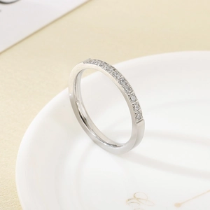 Detailed close-up of a silver stainless steel ring set with zircon stones on a white plate