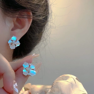 Elegant silver flower earrings with zircon and mother of pearl on a model's ear
