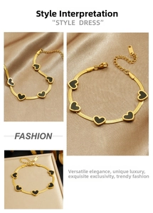 Detail of gold snake chain bracelet with five black heart pendants and lobster clasp