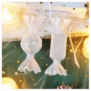 Dettaglio di decorazioni a caramella bianche traslucide con glitter argento e nastrini