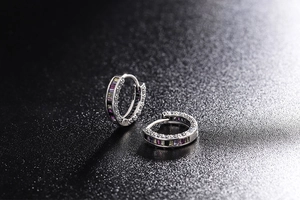 Macro view of silver hoop earrings with rainbow gemstones and sparkling starburst light