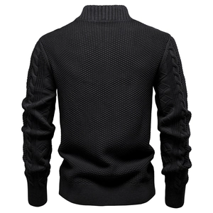 Dettaglio maglione nero in maglia con motivi a treccia e trama a nido d'ape