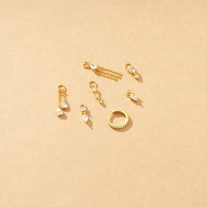 Detail of gold plated earring charms set with white cubic zirconia on textured background