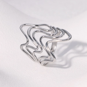 Detail of silver wavy irregular hollow stainless steel ring on white textured background