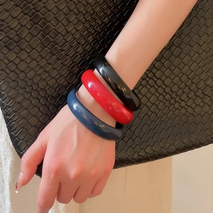 Close-up of three polished thick resin bangles in black, red, and blue colors