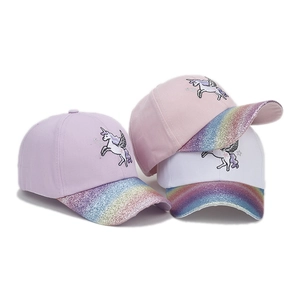 Detail of kids unicorn baseball caps featuring rainbow glitter brims and fine embroidery
