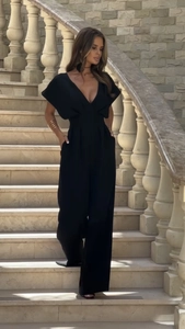 Elegant woman in black V-neck wide leg jumpsuit on classic outdoor stone steps