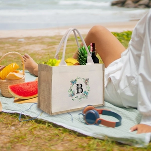 Detail of linen canvas tote bag with letter B on beach background for picnic style