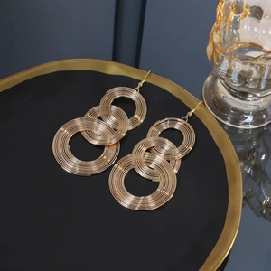 Macro detail of layered gold geometric circle drop earrings on a premium black display tray