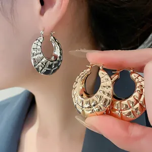 Textured gold and silver chunky hoop earrings with a woven checkered metal pattern
